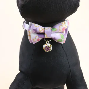 Pet collar detail view featuring a purple floral print bow and cute bell pendant for cats.