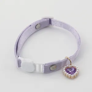 Detailed view of a purple satin pet collar featuring a white cat buckle and pearl heart pendant.