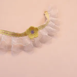 Close-up detail shot of cute pet lace collar with yellow knitted flower and ribbon.