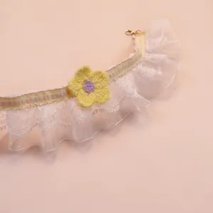 Close-up of lace pet collar detail featuring a cute handmade yellow crochet flower and pink ribbon.