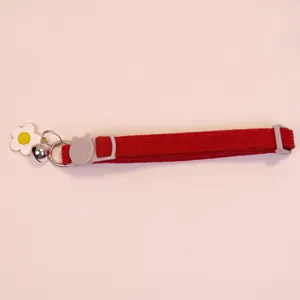 Red corduroy pet collar detail with cute flower charm, metal bell, and cat safety buckle.