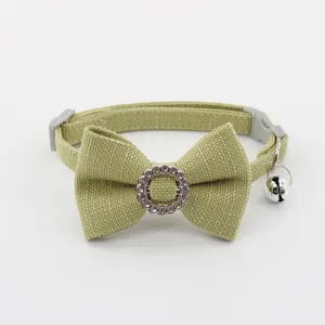 Close-up detail of green pet collar with bowknot, rhinestone circle buckle and hanging silver bell.