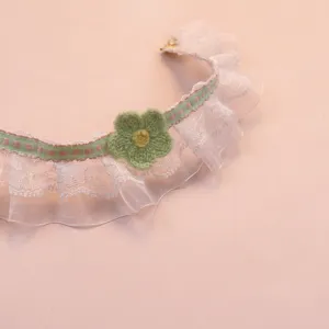 Detailed close-up of cute floral lace pet collar with green knitted flower and pink ribbon.