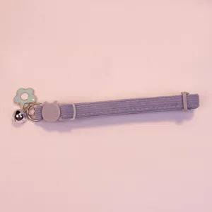 Detail shot of purple corduroy pet collar with cute bell, flower charm and safe cat buckle.