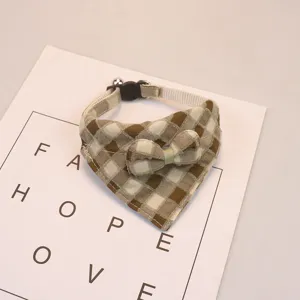 Closeup of cute brown plaid pet bib collar featuring sweet bowknot and bell details.