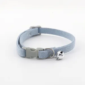 Detailed shot of a light blue denim pet collar with grey plastic buckle and a small silver bell.