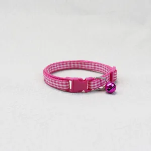 Close-up of pink plaid pet collar detail with cute bell and buckle, soft woven fabric design.