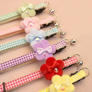 Detailed view of cute plaid pet collar featuring soft plush flower, bow and small bell.