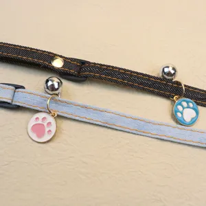 Close-up detail of adjustable pet denim collar featuring cute paw pendant and jingling bell.