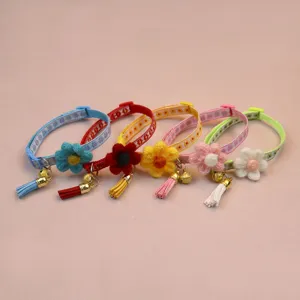 Detailed view of colorful pet collars featuring cute knitted flowers, tassels, and bells.