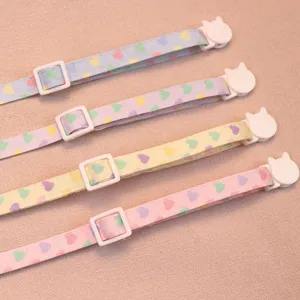 Close up detail of colorful heart pattern pet cat collars with cute white cat shaped buckles.