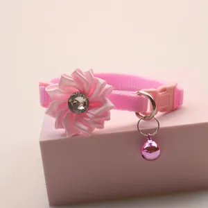 Close-up detail of the pink pet collar featuring a ribbon flower, crystal, and a hanging bell.
