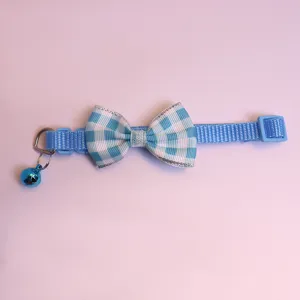 Détail de collier pour animal à carreaux bleu et blanc, avec nœud mignon et petite cloche.