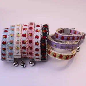 Close-up detail of cute apple print pet collars with delicate lace trim and sweet hanging bells.