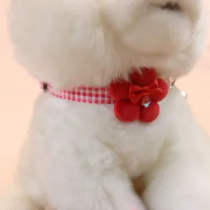 Close-up detail of red and white grid pet collar with cute plush flower and bow for cats dogs.