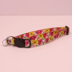 Close-up detail of the floral pet cat collar featuring a secure black safety buckle and bell.