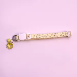 Detailed shot of cute floral pet collar with yellow bell and flower pendant, safe buckle.