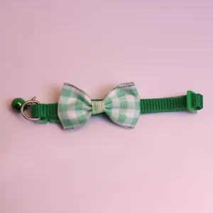 Détail de collier pour animal à carreaux verts avec joli nœud, petite cloche et boucle.