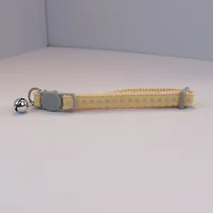 Close-up detail of the cute yellow checkered pet collar with cat face buckle and bell.