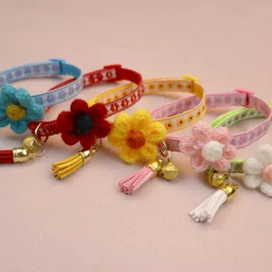 Detail shot of colorful pet collars featuring cute knitted flowers, tassels, and bells. Close-up view.