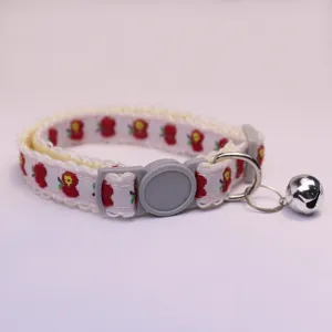 Close up of cute pet collar with apple print, lace trim, grey buckle and silver bell.