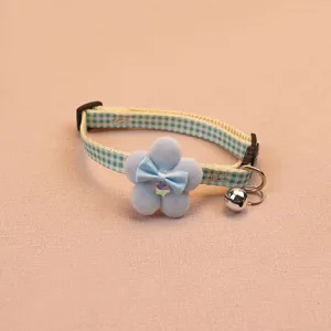 Close-up detail of the cute blue plaid pet collar featuring a soft plush flower and crisp bell.