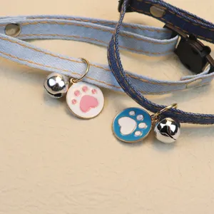 Denim cat collar with cute bell and paw print charm, adjustable and stylish pet accessory.