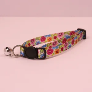 Floral cat collar detail shot featuring safety buckle and metal bell accessory