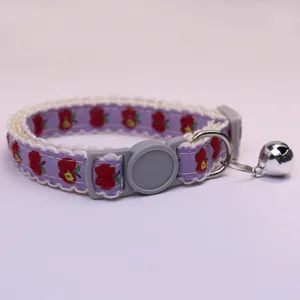 Close-up detail of cute purple pet collar with apple pattern, white lace and ringing bell.