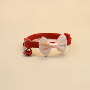 Collier pour animal rouge avec nœud beige et clochette, vue rapprochée de l'accessoire chat.
