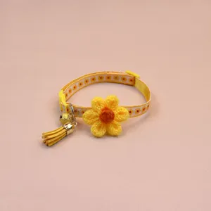 Yellow cat collar detail featuring a knitted flower, bell, and cute tassel pendant.