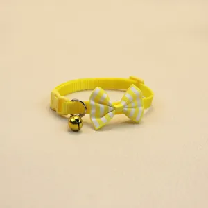 Gros plan détaillé du collier pour animal jaune avec un nœud rayé mignon et une cloche.