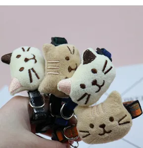 Close-up detail of cute plush cat head pet collar, soft fabric with adjustable strap design.