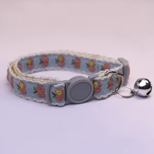 Cute blue apple embroidered pet collar detail closeup with metal bell and plastic buckle.