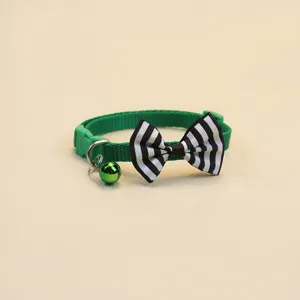 Détail de collier pour animal vert avec nœud papillon rayé et petite cloche mignonne.