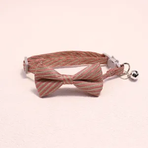 Close-up detail shot of the pet collar bow tie, showing the striped texture and metal bell.