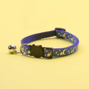 Detailed view of blue cat collar with gold moon star print, cat face buckle and bell.