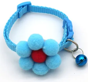Blue pet collar detail showcasing plush sunflower pom-pom decor and small metal bell.