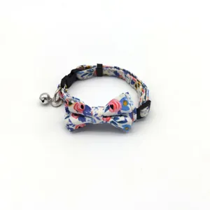 Floral cat collar detail featuring a cute bowknot and a silver bell on blue patterned fabric.