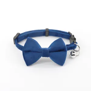 Close-up of blue velvet pet collar with bow and bell, soft texture and secure buckle detail.