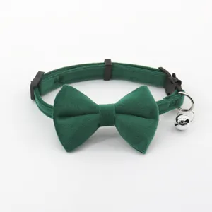 Green velvet pet collar with bow and bell for cats and small dogs close up detail.