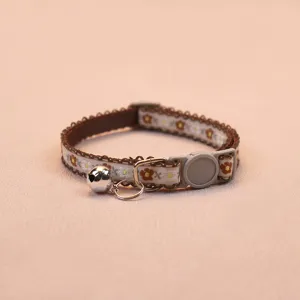 Close-up detail of a charming floral cat collar with a cute silver bell and safety buckle.