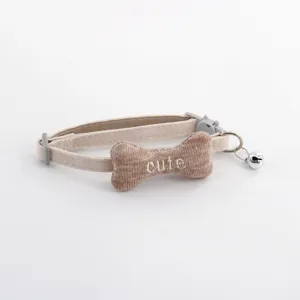 Cute pet collar with stuffed bone detail and bell, comfortable beige design for cats and dogs.