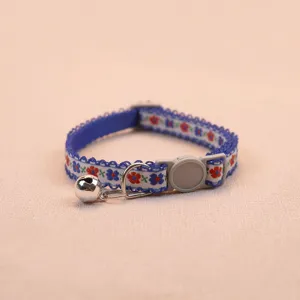 Close-up detail of blue floral pet collar with safety buckle and bell, neat stitching.