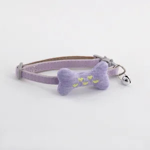 Purple pet collar detail featuring stuffed bone, yellow embroidered hearts, and metal bell.