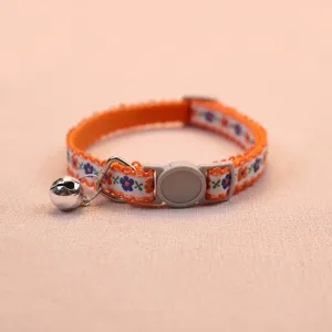 Close-up view of the orange floral cat collar featuring a safety buckle and silver bell.