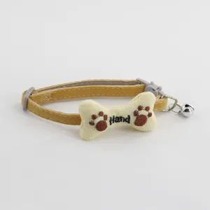 Close-up detail of cute pet collar featuring embroidered bone accessory, paw prints, and bell.