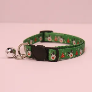 Christmas pet collar detail view, green fabric with cute reindeer and tree patterns, metal bell.