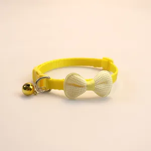 Close-up detail of the cute yellow pet collar with fluffy bow and golden bell for cats.