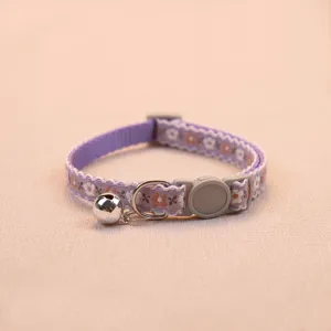 Detail of purple floral cat collar with safety buckle and bell, soft woven fabric pet accessory.